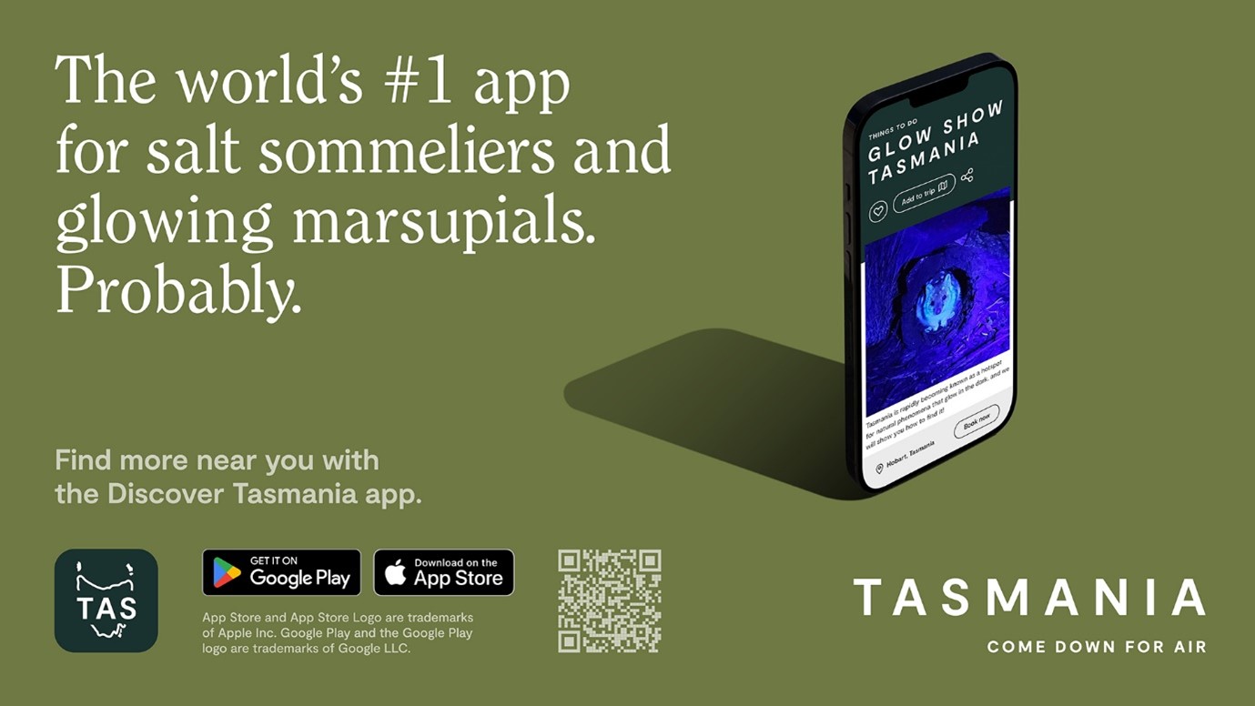 White text over an olive-green background reads: "The world's #1 app for salt sommeliers and glowing marsupials. Probably". Below this in smaller white text, reads: "Find more near you with the Discover Tasmania app." Some icons display the forest-green Discover Tasmania app logo, the Google Play download link, the App Store download link, a QR code linking to the Discover Tasmania app and the "Tasmania - Come Down For Air" logo in white. A graphic shows a phone displaying the Discover Tasmania app on its screen.