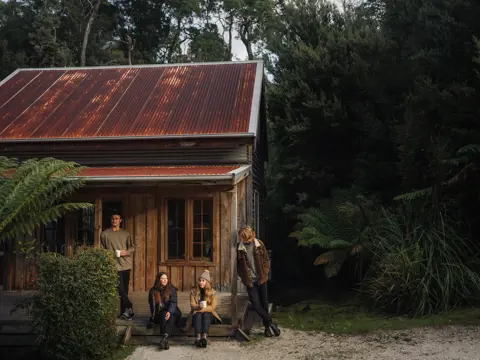 Guests on the porch of a timber miners cottage at Corinna Wilderness Village, takayna / Tarkine, Tasmania's West Coast