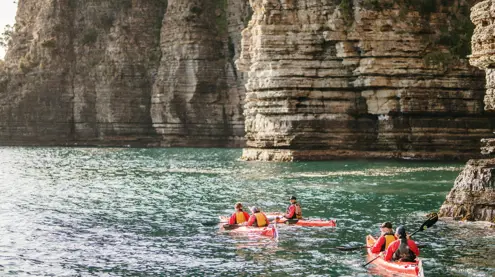 Kayakers paddling beneath tall cliffs with Southern Sea Ventures, Tasman National Park on Turrakana / Tasman Peninsula
