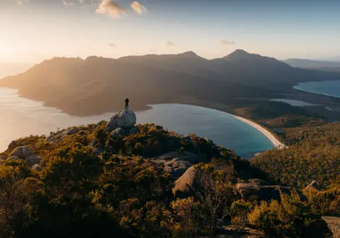 Person on a granite outcrop overlooking Wineglass Bay, Freycinet National Park, Tasmania
