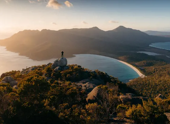 Person on a granite outcrop overlooking Wineglass Bay, Freycinet National Park, Tasmania