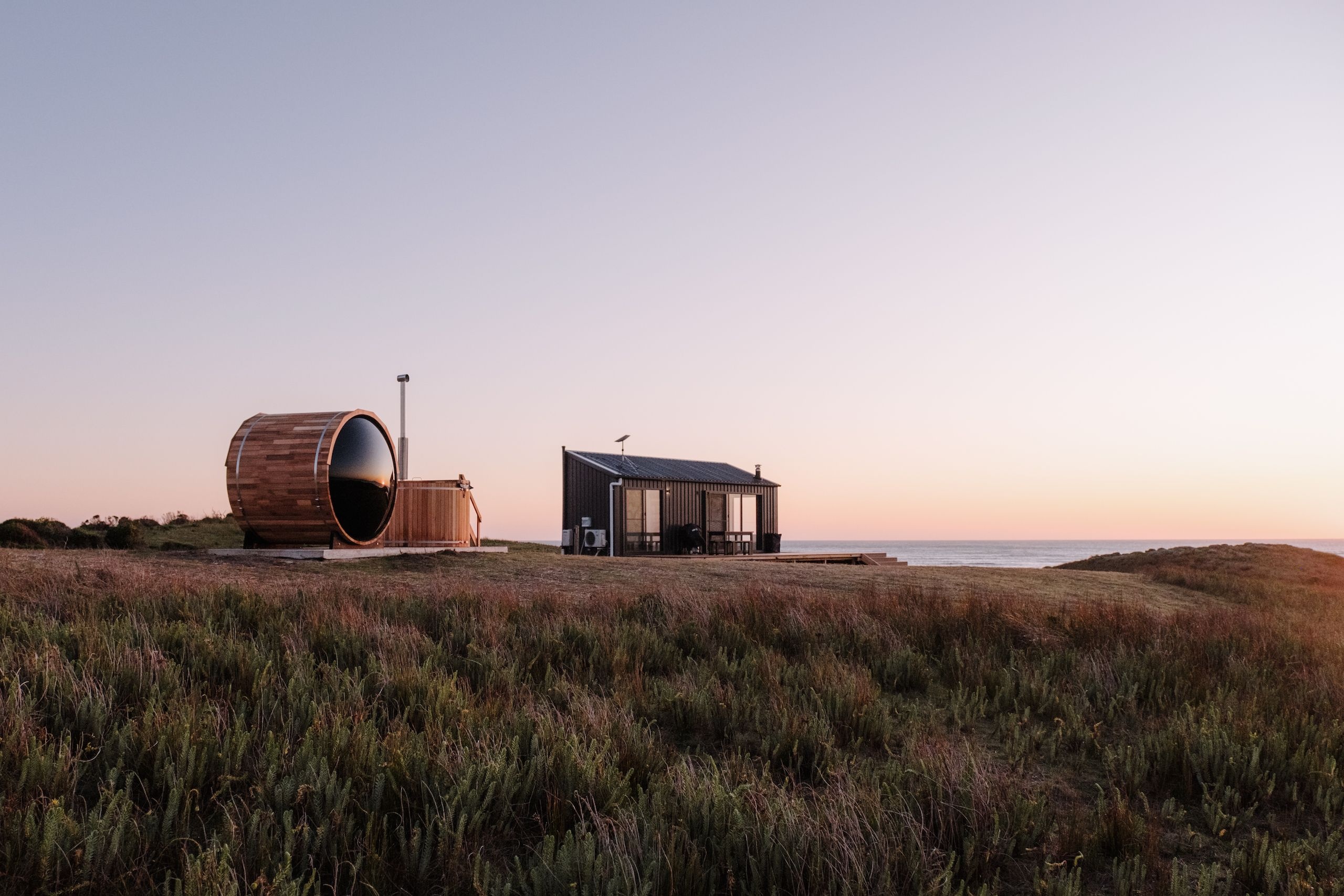 A barrel sauna and small cabin overlooking the sea at Red Rock Hut, King Island, Tasmania