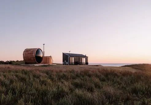 A barrel sauna and small cabin overlooking the sea at Red Rock Hut, King Island, Tasmania