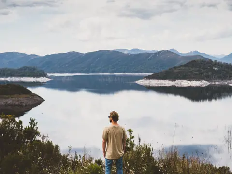 A person looking out over Lake Gordon with mountains in the distance, Strathgordon, Southwest National Park, Tasmania