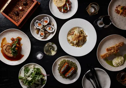 A spread of plated dishes including oysters, salad and wine at Mövenpick Hotel Hobart, Tasmania